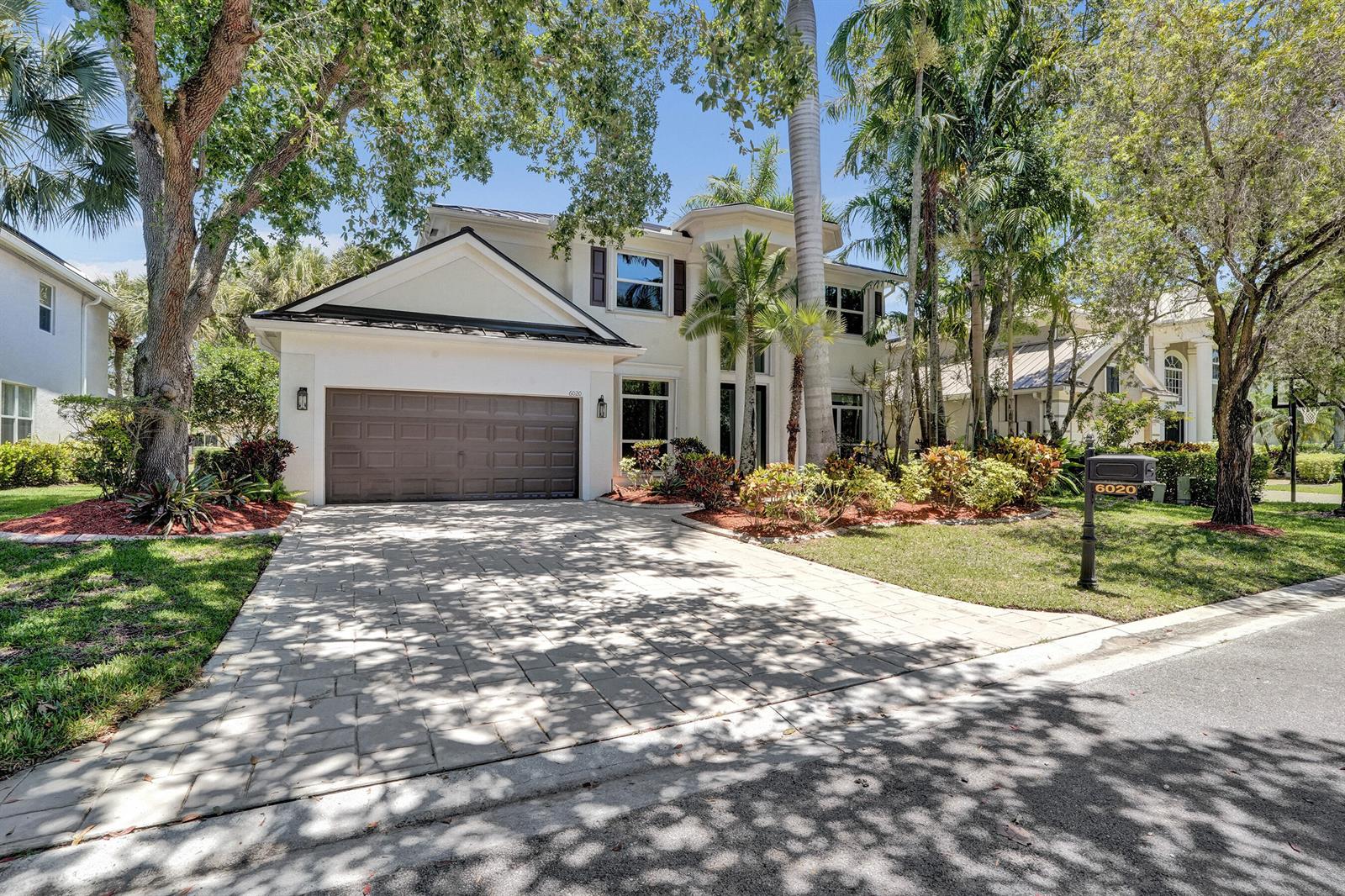 A two-story house with a paved driveway, a brown garage door, and lush landscaping — 6020 NW 104th Lane, Parkland FL 33076, PARKLAND, FL