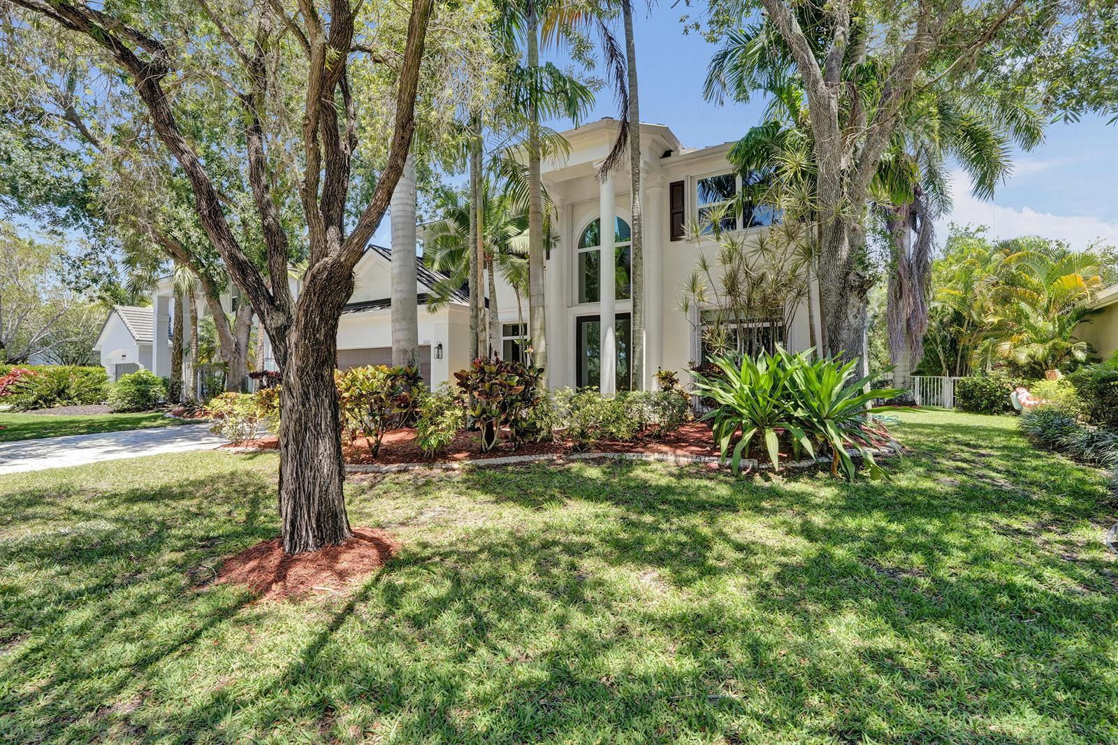 A two-story white house with a tall arched window and palm trees in the yard — 6020 NW 104th Lane, Parkland FL 33076, PARKLAND, FL
