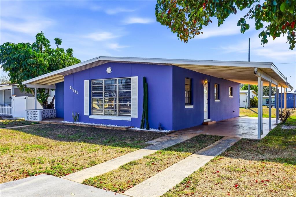 A bright purple single-story house features a front carport, a large window, and a cactus — 21283 MIDWAY BOULEVARD, PORT CHARLOTTE, FL