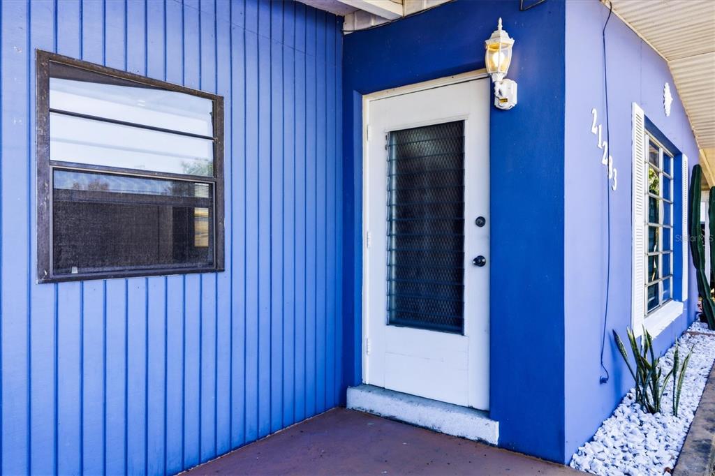 A bright blue exterior wall features a white front door, two windows, and a light — 21283 MIDWAY BOULEVARD, PORT CHARLOTTE, FL