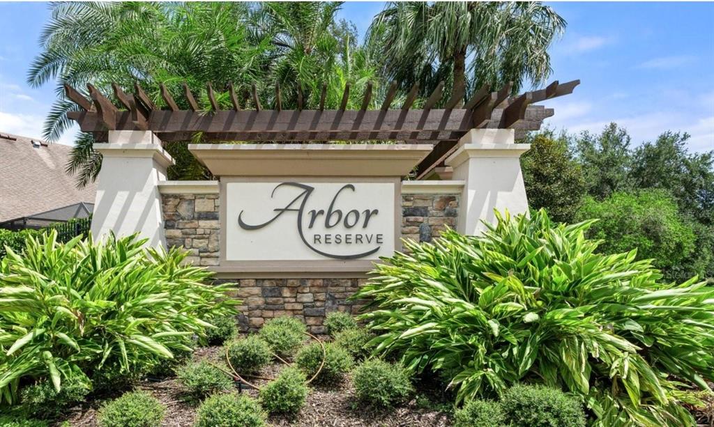 A stone and stucco monument sign for Arbor Reserve stands behind lush green landscaping — 5711 ARBOR WOOD COURT, BRADENTON, FL