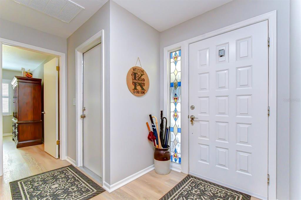 An entryway features a white front door with a stained-glass sidelight and light wood flooring — 8935 RUGER DRIVE, NEW PORT RICHEY, FL