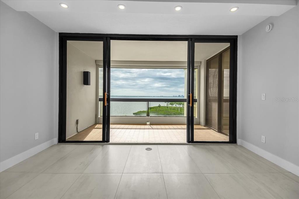 A room with light-colored tile flooring features large sliding glass doors opening to a balcony — 2020 HARBOURSIDE DRIVE UNIT 446, LONGBOAT KEY, FL