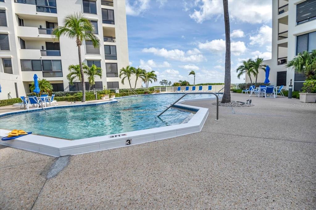A swimming pool with a three-foot depth marker sits between two multi-story apartment buildings — 2020 HARBOURSIDE DRIVE UNIT 446, LONGBOAT KEY, FL