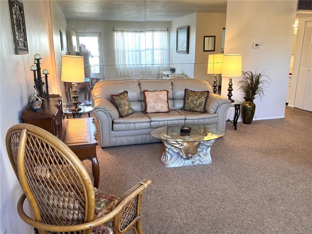 A living room features a beige leather sofa, a glass coffee table, and mirrored walls — 4480 IRONWOOD CIRCLE UNIT 308A, BRADENTON, FL