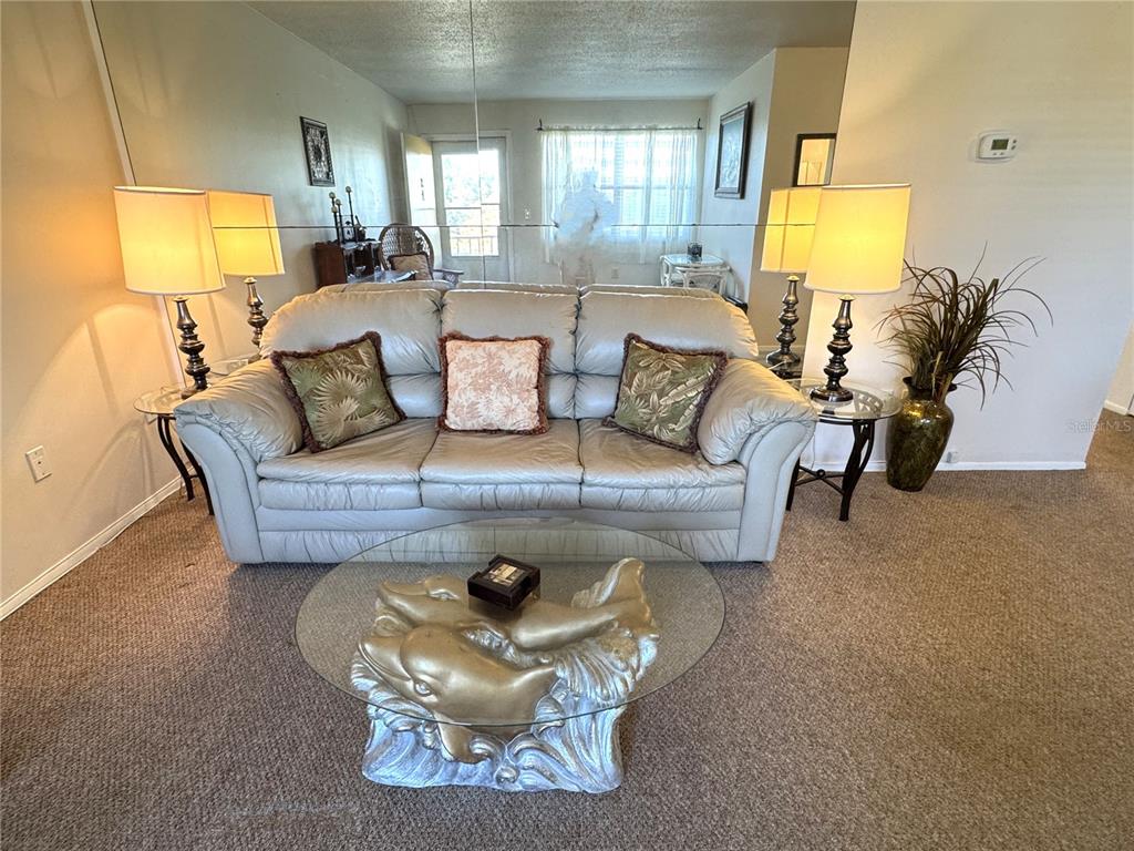 A living room features a light-colored leather sofa, a dolphin-themed coffee table, and mirrored walls — 4480 IRONWOOD CIRCLE UNIT 308A, BRADENTON, FL