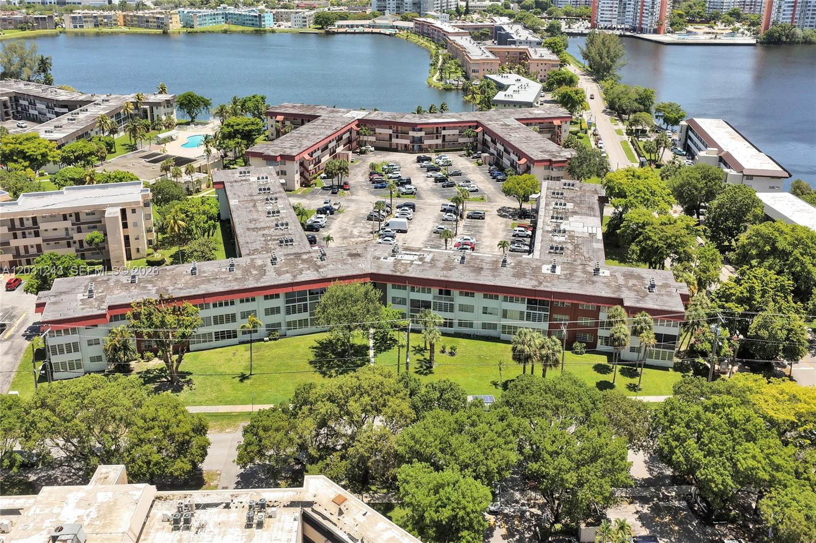 An aerial view shows a multi-story apartment complex with a central parking lot and landscaping — 1400 NE 191st St # 343, Miami FL 33179, MIAMI, FL