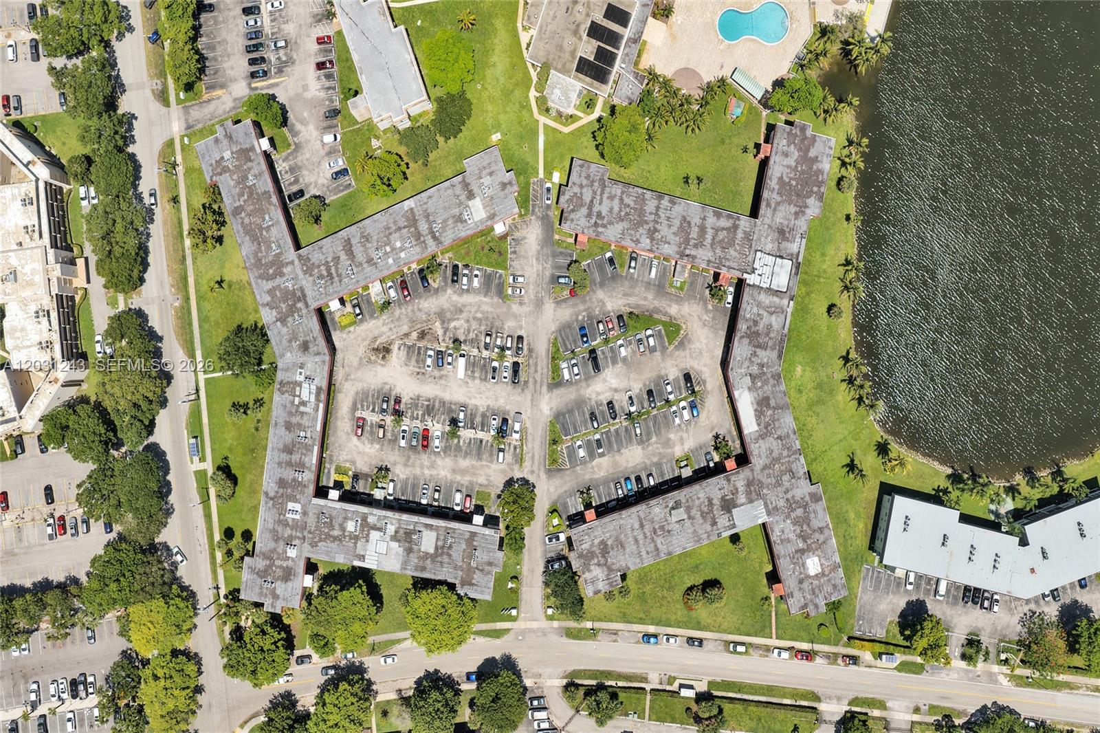 An aerial view shows a multi-wing apartment complex with a central parking lot and pool — 1400 NE 191st St # 343, Miami FL 33179, MIAMI, FL