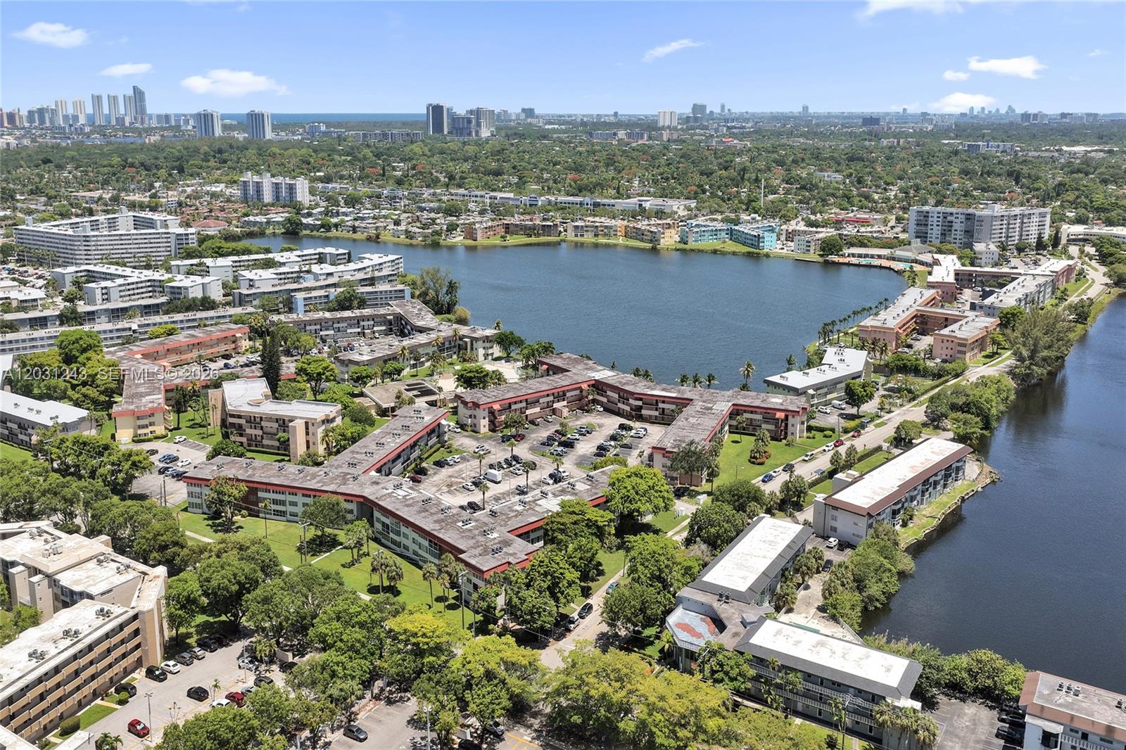 An aerial view shows multiple apartment complexes situated around a large lake — 1400 NE 191st St # 343, Miami FL 33179, MIAMI, FL