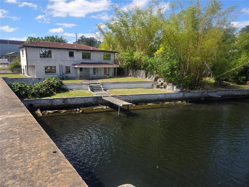 A two-story house with a tiled roof sits beside a body of water with a dock — 8002 N FLORIDA AVENUE, TAMPA, FL