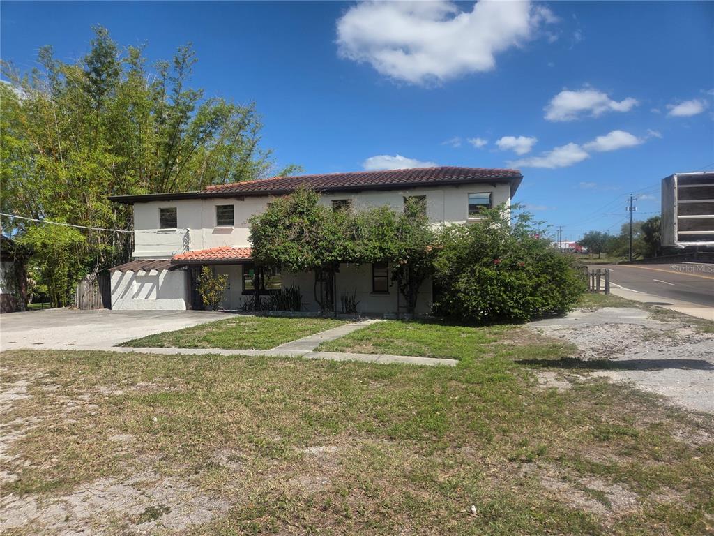 A two-story stucco house with a tile roof sits next to a road — 8002 N FLORIDA AVENUE, TAMPA, FL
