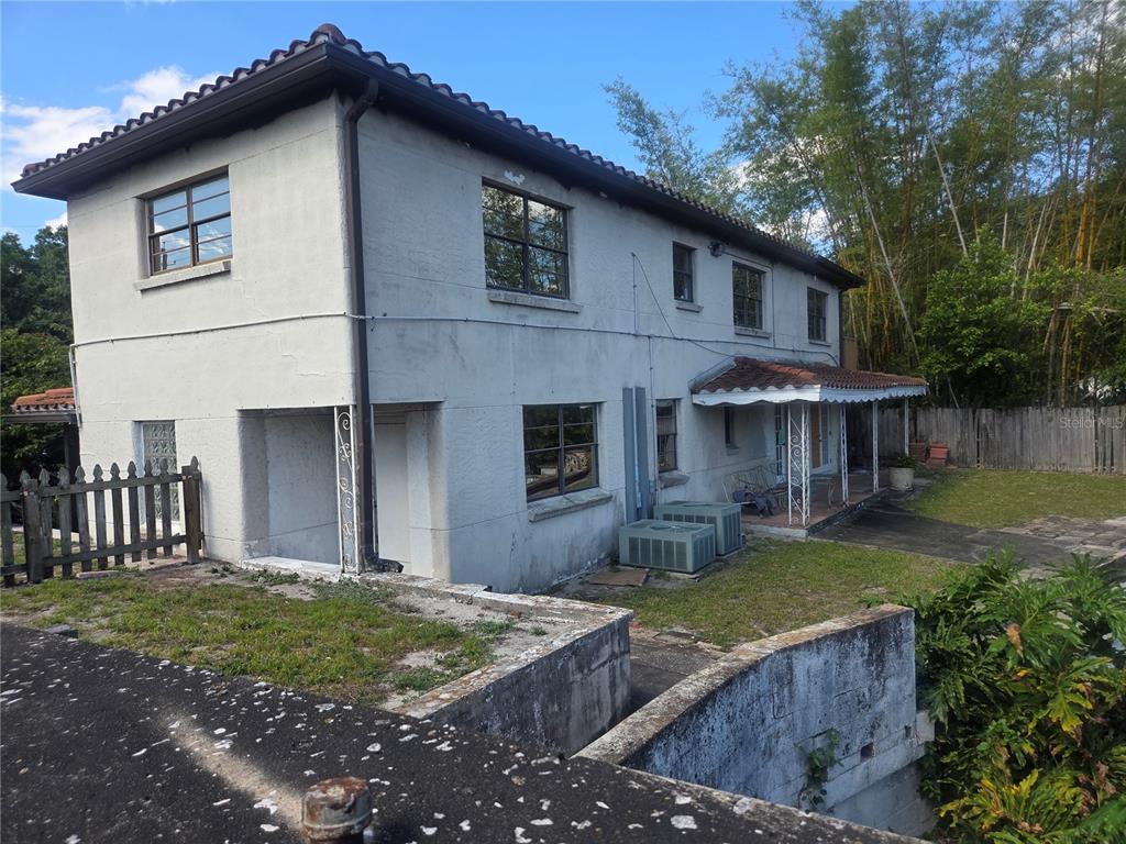 A two-story stucco house with a tiled roof, metal awning, and an outdoor concrete patio — 8002 N FLORIDA AVENUE, TAMPA, FL