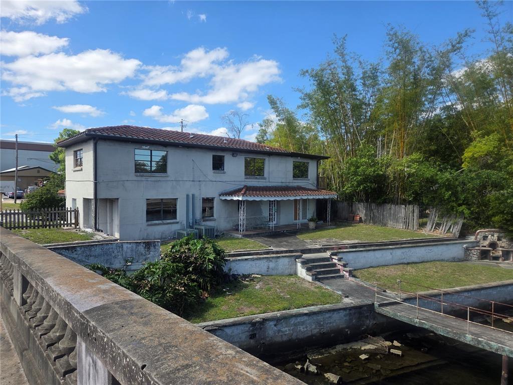 A two-story house with a tiled roof sits beside a concrete canal and patio — 8002 N FLORIDA AVENUE, TAMPA, FL