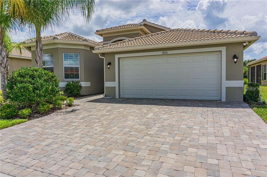 A beige house with a tiled roof, a two-car garage, and a paved driveway — 4836 GRAND BANKS DRIVE, WIMAUMA, FL