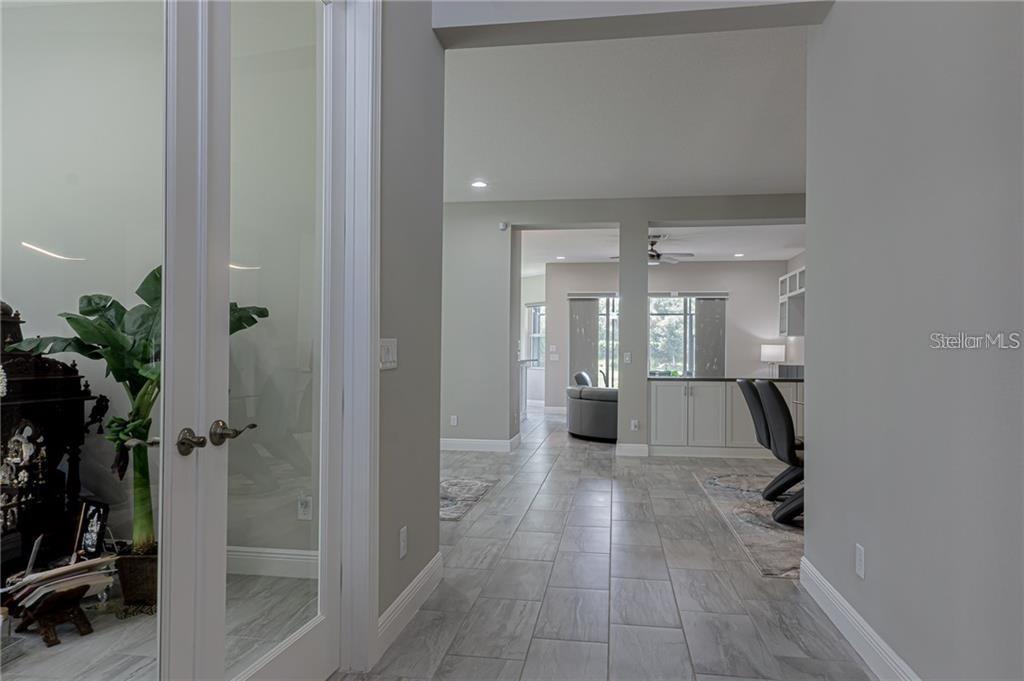 A hallway with gray tile flooring leads toward an open kitchen and living area — 4836 GRAND BANKS DRIVE, WIMAUMA, FL