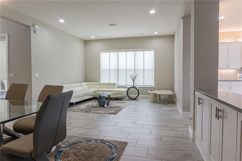 A living room with light tile floors, a white sectional sofa, and a glass coffee table — 4836 GRAND BANKS DRIVE, WIMAUMA, FL