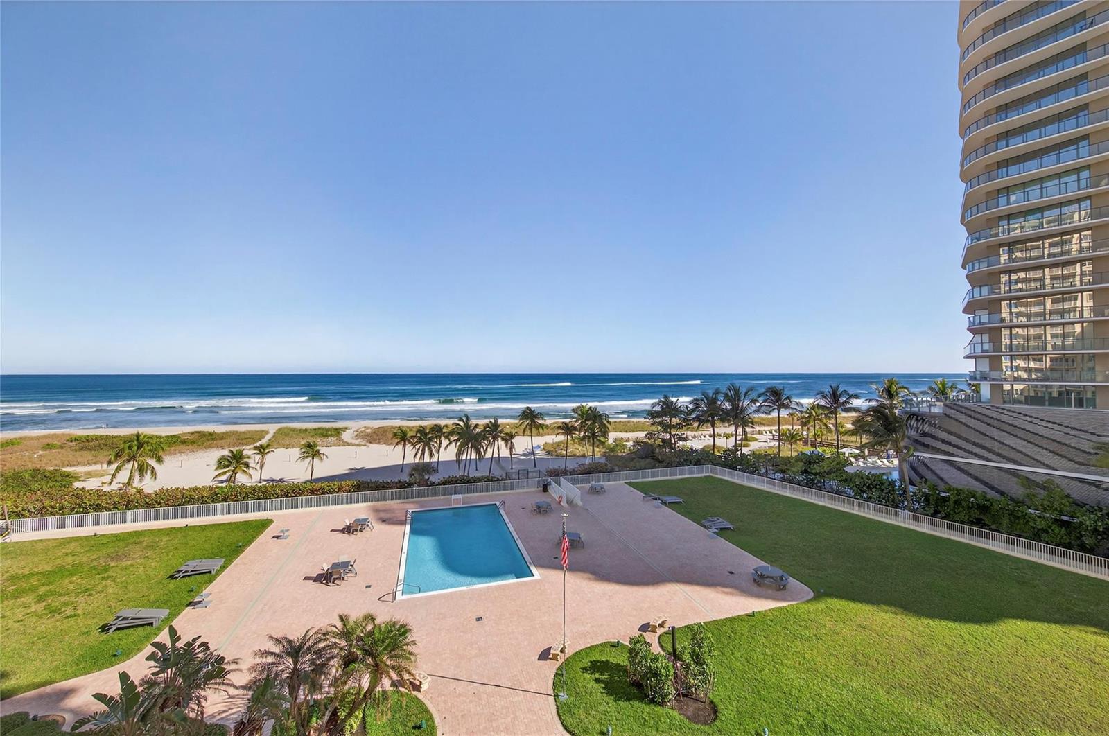 An elevated view of a swimming pool, grassy lawn, and beach with a high-rise building — 750 N Ocean Boulevard # 608, Pompano Beach FL 33062, POMPANO BEACH, FL