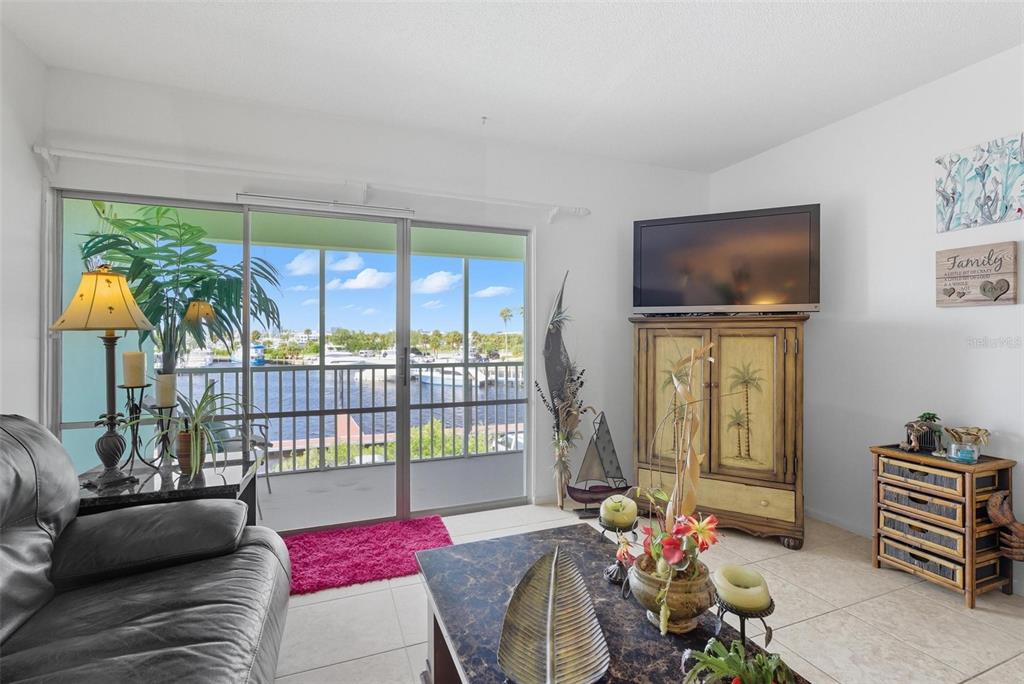 A living room features tile flooring, a television on a cabinet, and a sliding glass door — 715 S BEACH STREET UNIT 314D, DAYTONA BEACH, FL