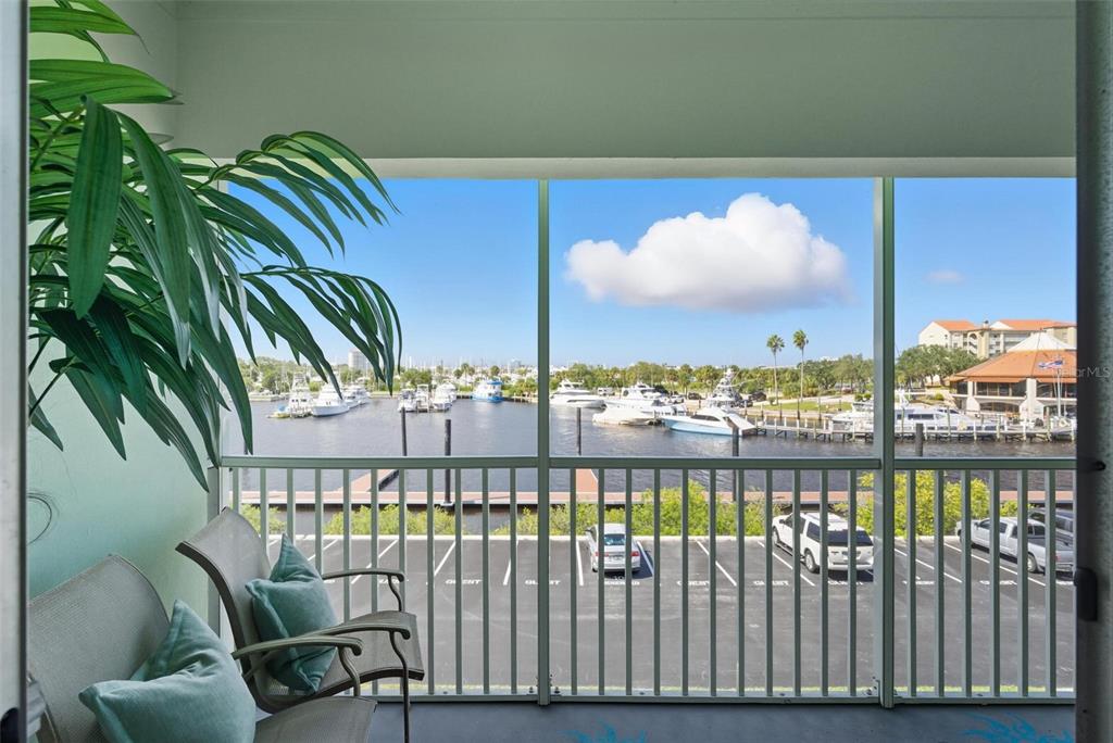 A screened balcony overlooks a parking lot, a marina with boats, and a blue sky — 715 S BEACH STREET UNIT 314D, DAYTONA BEACH, FL