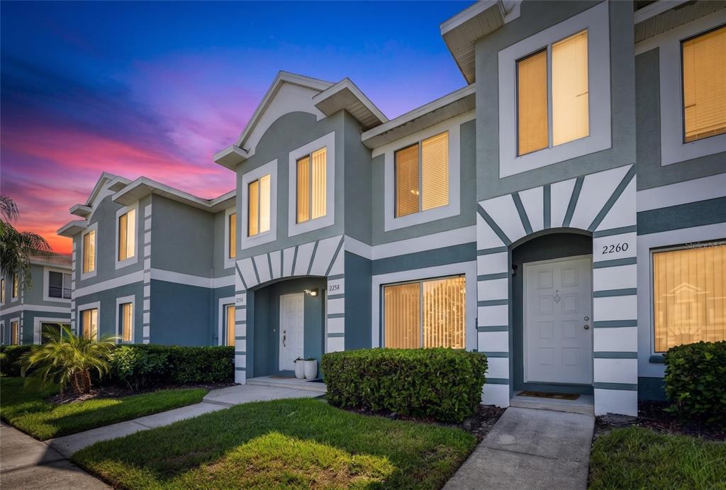 A two-story townhouse exterior features gray siding, white trim, and arched entryways at dusk — 2258 FLUORSHIRE DRIVE, BRANDON, FL