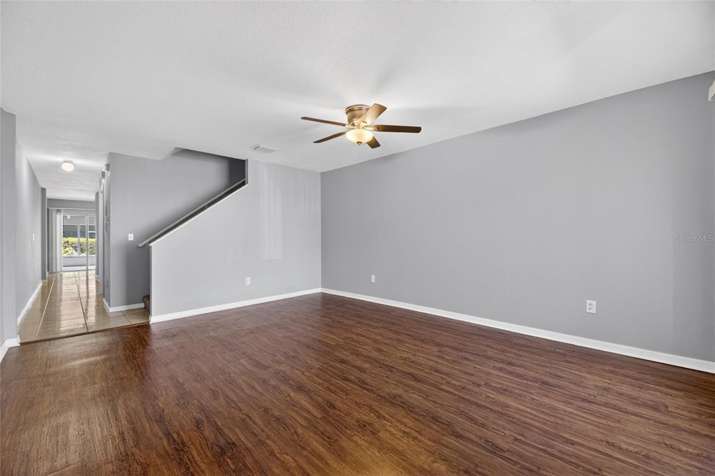 A living room features wood-look flooring, gray walls, a ceiling fan, and a staircase — 2258 FLUORSHIRE DRIVE, BRANDON, FL