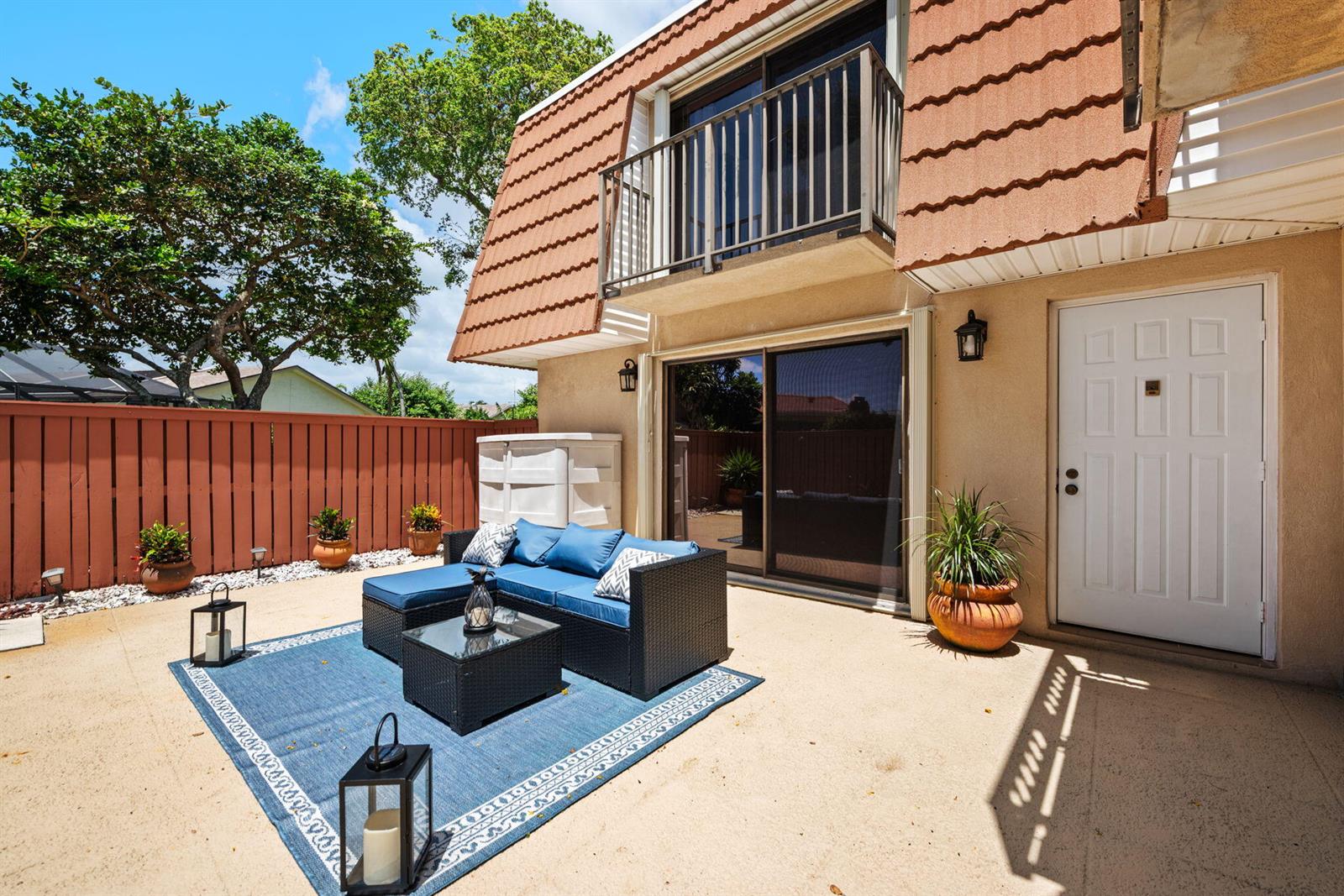 A patio features a blue sectional sofa, a rug, and a white door on a building — 2874 Waterford Drive S, Deerfield Beach FL 33442, DEERFIELD BEACH, FL