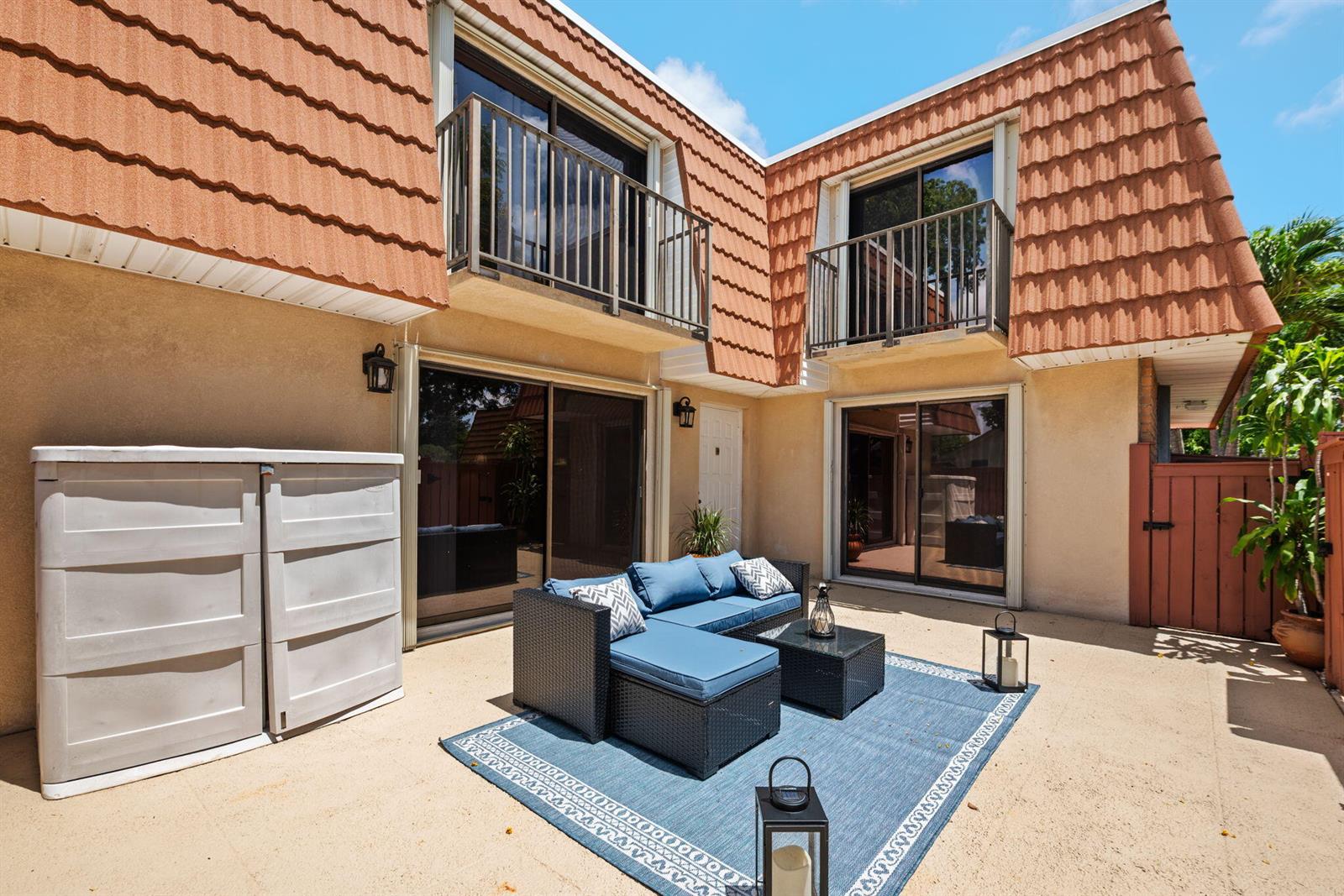 A patio features a blue sectional sofa, a rug, and two balconies on a two-story building — 2874 Waterford Drive S, Deerfield Beach FL 33442, DEERFIELD BEACH, FL