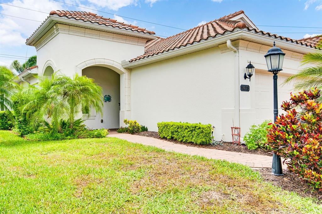 A single-story house with a tiled roof, stucco exterior, and a paved walkway to the entrance — 1418 CALLE GRAND STREET, BRADENTON, FL
