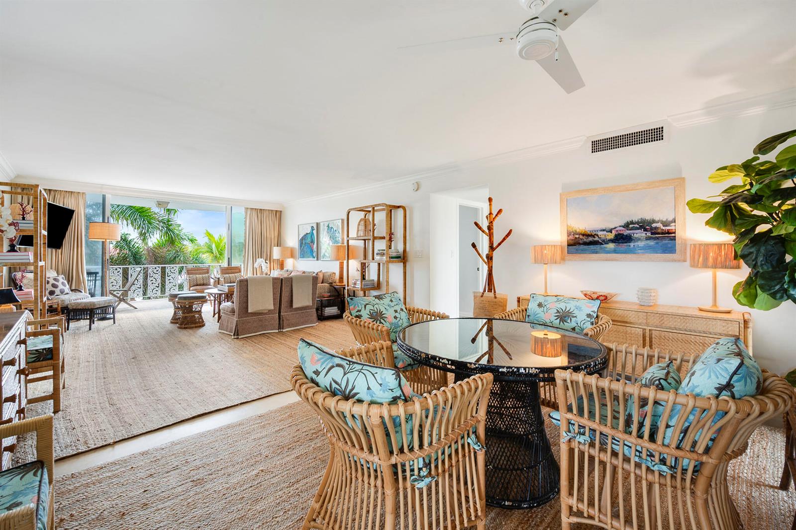 A bright living and dining area features rattan furniture, tropical decor, and a balcony view — 227 Australian Avenue # 3e, Palm Beach FL 33480, PALM BEACH, FL