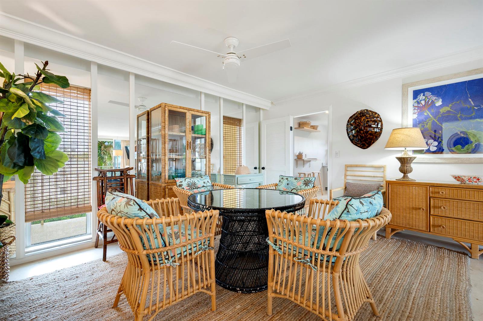 A dining area features a round glass table with four rattan chairs on a rug — 227 Australian Avenue # 3e, Palm Beach FL 33480, PALM BEACH, FL