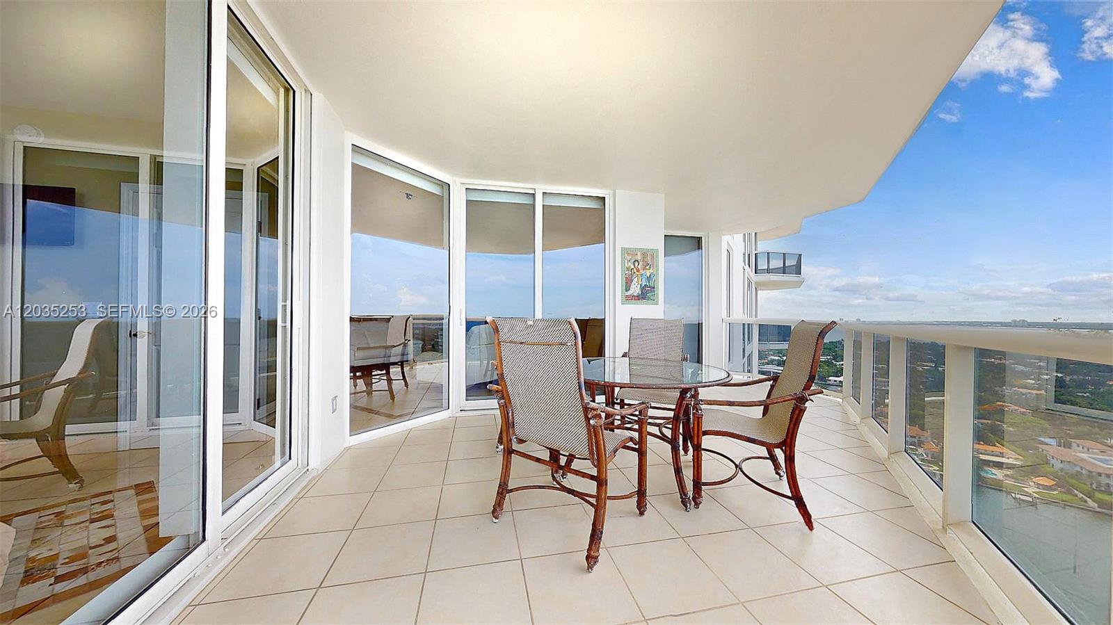 A tiled balcony features a glass-topped dining set and panoramic views of the water — 4779 Collins Ave # 2708, Miami Beach FL 33140, MIAMI BEACH, FL