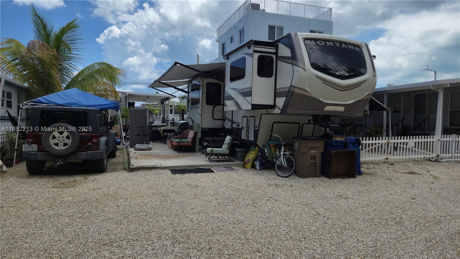 A Montana fifth-wheel RV is parked on a gravel lot next to a Jeep — 325 Calusa St lot 333, Key Largo FL 33037, KEY LARGO, FL