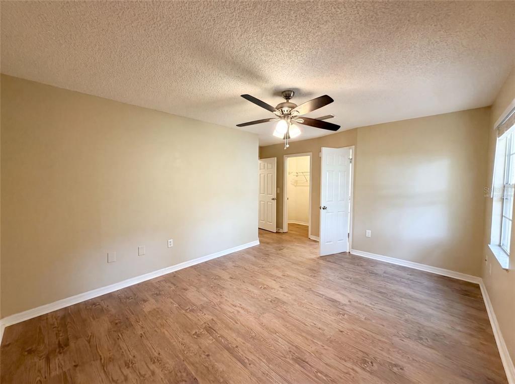 An empty bedroom features light-colored walls, wood-look flooring, a ceiling fan, and two white doors — 2715 LORRAINE DRIVE, LEESBURG, FL