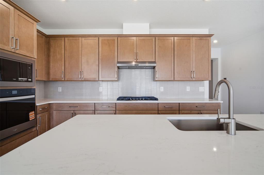 A kitchen features light wood cabinets, white countertops, a stainless steel range, and an island — 7629 MARINA BAY COVE, PALMETTO, FL
