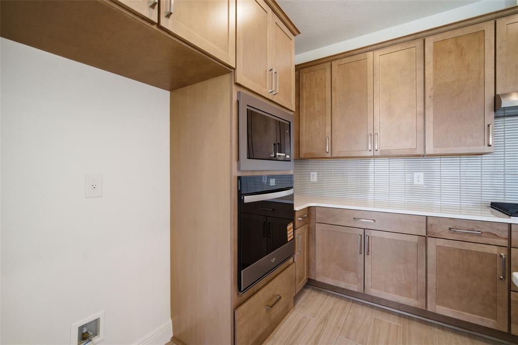 A kitchen features light wood cabinets, stainless steel appliances, and a white tiled backsplash — 7629 MARINA BAY COVE, PALMETTO, FL