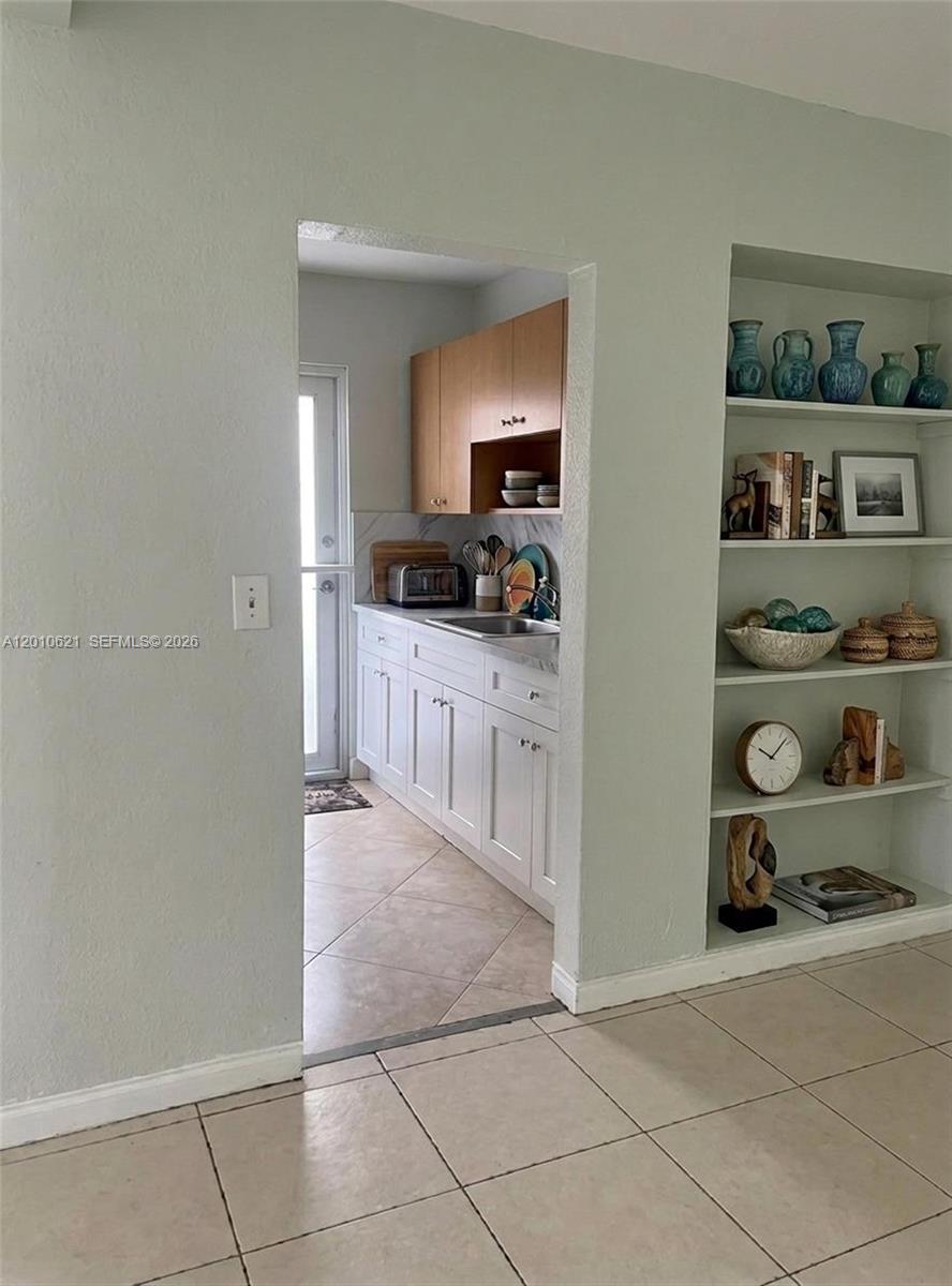 A view through a doorway shows a kitchen with white cabinets and wood-toned upper cabinets — 2412 SW 11th St # 1, Miami FL 33135, MIAMI, FL