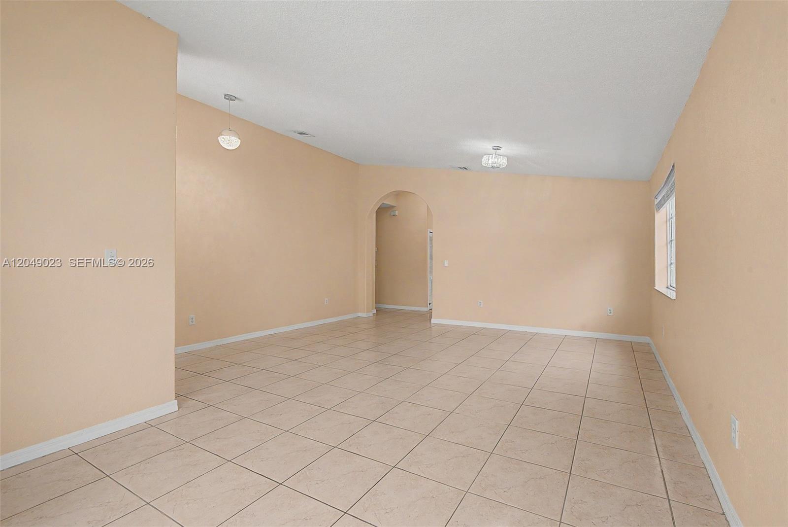 An empty room with beige walls, light-colored tile flooring, and an arched doorway — 15339 SW 32 TER # 0, Miami FL 33185, MIAMI, FL