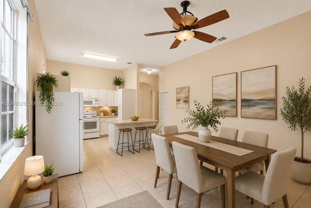 A dining area with a wooden table and chairs sits adjacent to an open kitchen — 15339 SW 32 TER # 0, Miami FL 33185, MIAMI, FL