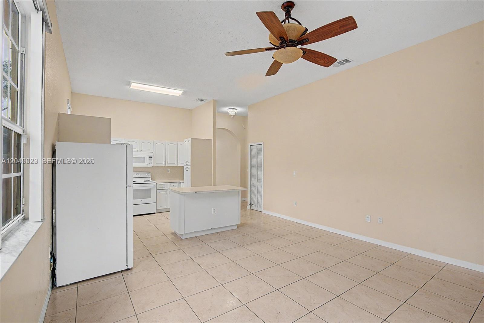 This kitchen and living area features tile flooring, white cabinets, and a ceiling fan — 15339 SW 32 TER # 0, Miami FL 33185, MIAMI, FL