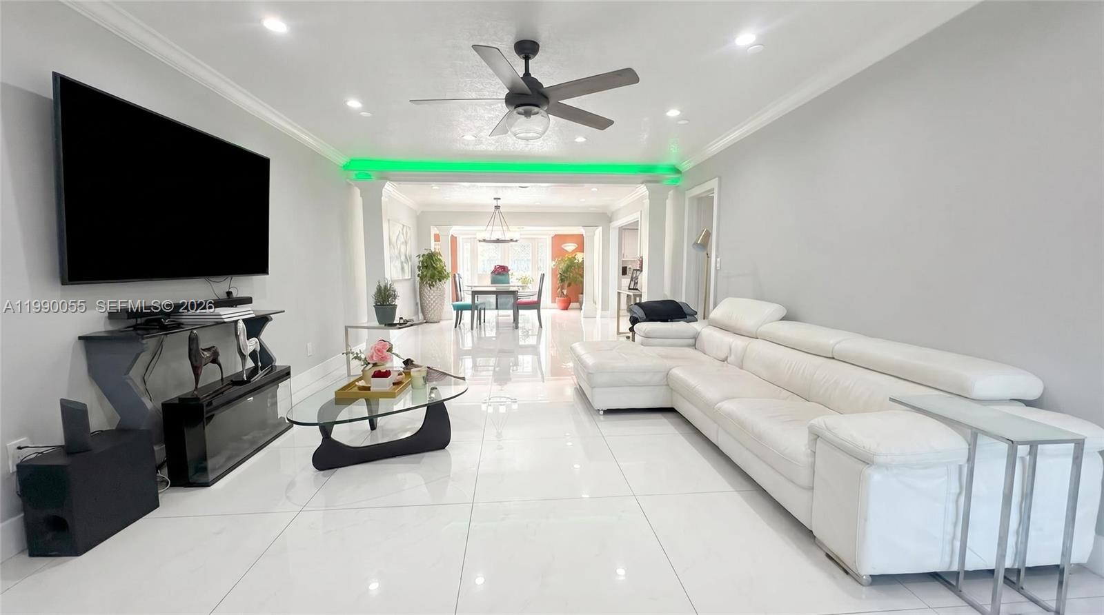 A living room features white tile floors, a white sectional sofa, and green accent lighting — 136 SE 2nd Ct, Dania Beach FL 33004, DANIA BEACH, FL