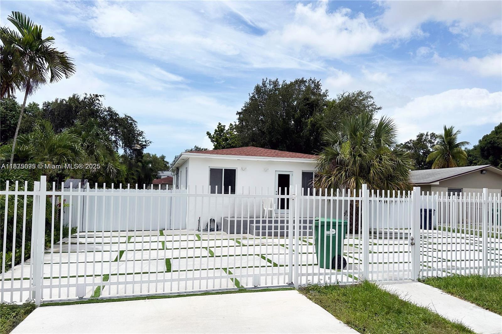 A white house with a red roof sits behind a white metal fence and gate — 2740 NW 49th St, Miami FL 33142, MIAMI, FL