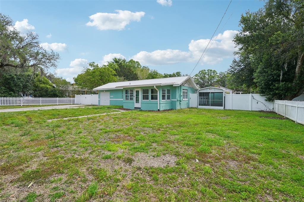 A light green single-story house with a metal roof sits on a grassy lot — 12385 SE 135TH COURT, OCKLAWAHA, FL