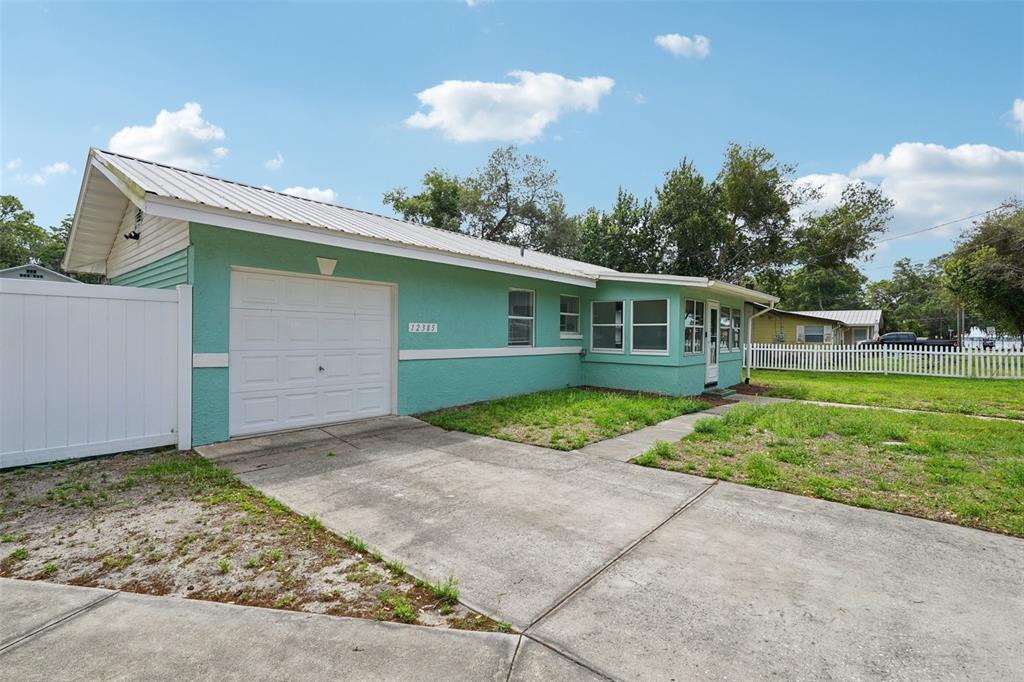 A light green house with a white garage door and a concrete driveway — 12385 SE 135TH COURT, OCKLAWAHA, FL