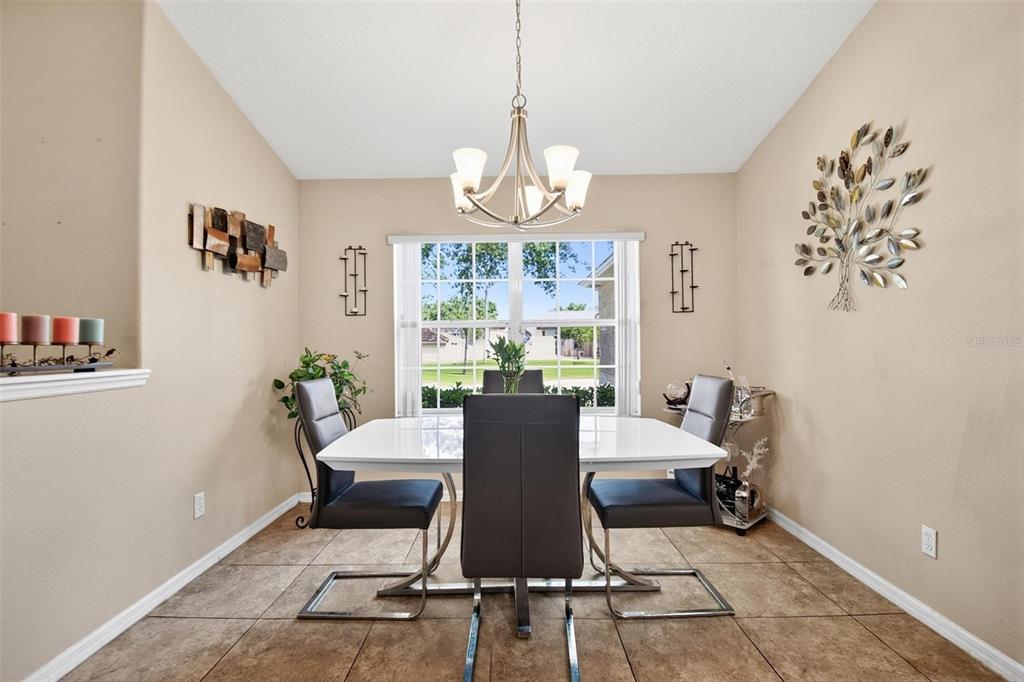 A dining room features a white table, four dark chairs, and a central chandelier — 203 FRONTIER DRIVE, PALM COAST, FL