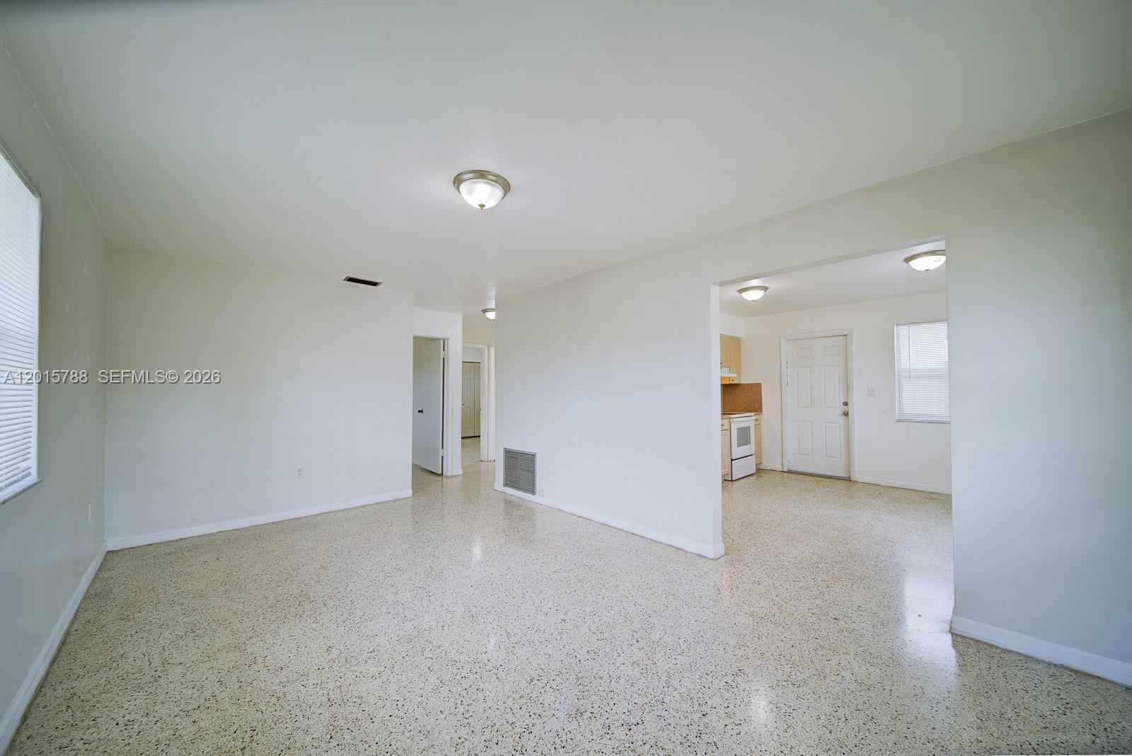 An interior view shows a living area with terrazzo flooring and a connected kitchen — 7358 - 7360 SW 23rd St, Miami FL 33155, MIAMI, FL