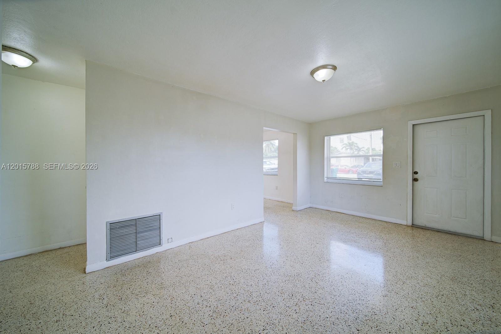 An empty room features white walls, a light-colored terrazzo floor, and a white entry door — 7358 - 7360 SW 23rd St, Miami FL 33155, MIAMI, FL