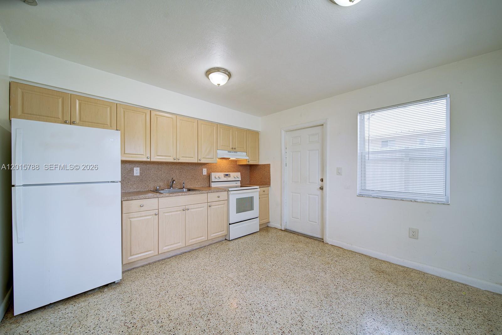 A kitchen features light wood cabinets, white appliances, and speckled flooring — 7358 - 7360 SW 23rd St, Miami FL 33155, MIAMI, FL