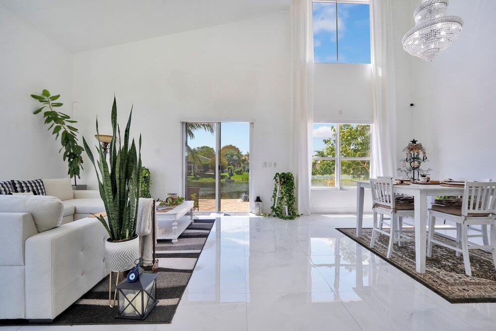A bright living and dining area with high ceilings, white tile floors, and lake views — 2242 SW 130th Terrace, Miramar FL 33027, MIRAMAR, FL