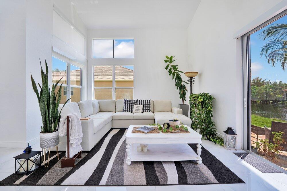A bright living room features a white sectional sofa, striped rug, and large sliding doors — 2242 SW 130th Terrace, Miramar FL 33027, MIRAMAR, FL