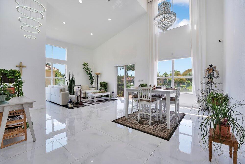 A bright, open-concept living and dining area with high ceilings, white tile floors, and chandeliers — 2242 SW 130th Terrace, Miramar FL 33027, MIRAMAR, FL